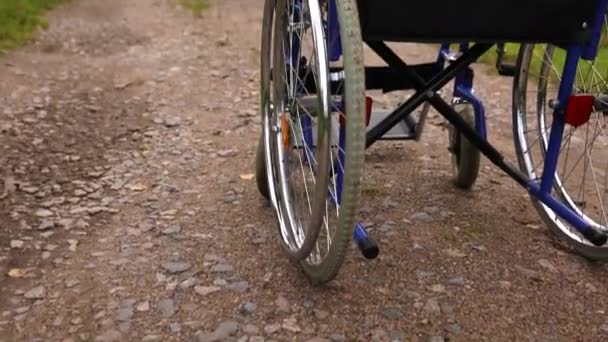 Empty wheelchair standing on road waiting for patient services. Invalid chair for disabled people parked outdoor in nature. Handicap accessible symbol. Health care medical concept. — Stock Video