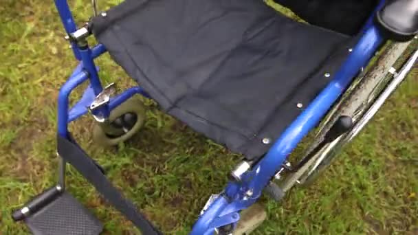 Lege rolstoel op gras in ziekenhuispark wachtend op patiëntenzorg. Ongeldige stoel voor gehandicapten geparkeerd buiten in de natuur. Handicap toegankelijk symbool. Gezondheidszorg medisch concept. — Stockvideo