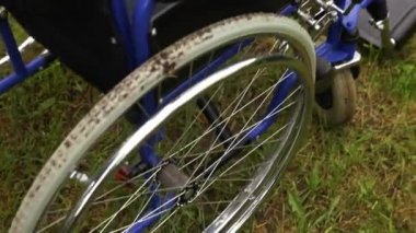 Hastane parkında çimlerde bekleyen boş tekerlekli sandalye hasta hizmetlerini bekliyor. Doğada park etmiş engelliler için geçersiz sandalye. Özürlü erişilebilir sembol. Sağlık hizmeti tıbbi konsepti.