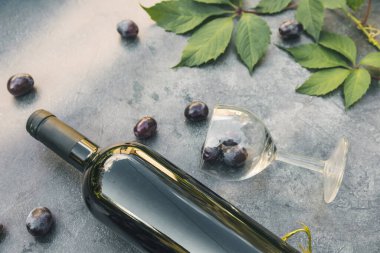 Bir şişe kırmızı şarap, yeşil üzüm, şarap kadehi ve olgun üzümlü eskimiş taş masa arkaplanı. Metin için üst görünüm kopyalama alanı. Şarap dükkanı şarap dükkanı ya da şarap tatma konsepti