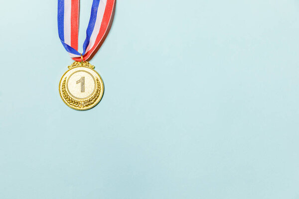 Simply flat lay design winner or champion gold trophy medal isolated on blue colorful background. Victory first place of competition. Winning or success concept. Top view copy space