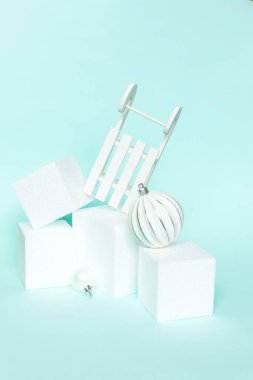 Kısaca kış nesneleri süslemesi ve küp şekilleri geometrik form podyumu izole edilmiş mavi pastel arka plan. Noel, yeni yıl kutlamaları için aralık zamanı. Kopyalama alanı