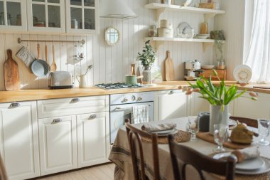 İskandinav klasiği beyaz ve ahşap çiçekli minimalist mutfak. Modern beyaz mutfak, çağdaş tarz iç tasarım. Boş parlak beyaz iç mekan, mutfak minimumu