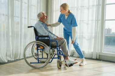 Emeklilik sağlık hizmetlerine destek ol. Hemşire tekerlekli sandalyedeki yaşlı adama yardım ediyor. Hasta ve kadın tıbbi bakım için huzurevinde. Engelli insanlar için tekerlekli sandalyede felçli bir adama bakan hemşire.