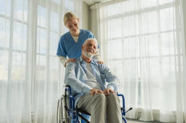 Emeklilik sağlık hizmetlerine destek ol. Hemşire tekerlekli sandalyedeki yaşlı adama yardım ediyor. Hasta ve kadın tıbbi bakım için huzurevinde. Engelli insanlar için tekerlekli sandalyede felçli bir adama bakan hemşire.