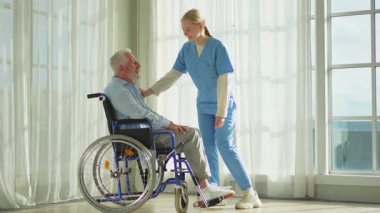 Emeklilik sağlık hizmetlerine destek ol. Hemşire tekerlekli sandalyedeki yaşlı adama yardım ediyor. Hasta ve kadın tıbbi bakım için huzurevinde. Engelli insanlar için tekerlekli sandalyede felçli bir adama bakan hemşire.