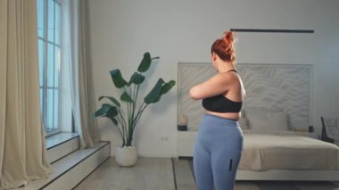 Fitness antrenmanı. Evde spor yapan bir kadın. Artı ev içinde spor egzersizi yapan beden bir kadın. Spor giyimli kız kilo vermek için ağırlık çalışması yapıyor. Spor ve zindelik