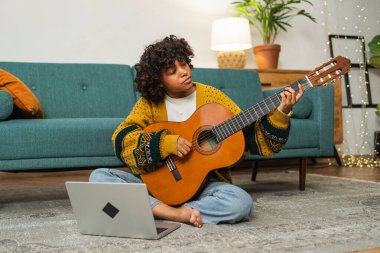 Blogger guitarist. Happy African American girl blogger playing guitar singing song recording vlog. Social media influencer woman streaming recording at home studio. Music content creator broadcast
