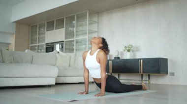 Yoga fitness antrenmanı. Sağlıklı Afrikalı kız evde yoga yapıyor. Pilates antrenmanı yapan bir kadın, yoga minderiyle spor yapıyor. Kız kilo vermek için antrenman yapıyor. Spor uygunluğu