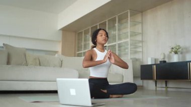 Yoga farkındalığı meditasyonu çevrimiçi. Afrikalı kadın evdeki bilgisayarında online derslerle yoga yapıyor. Lotus 'ta oturan kadın meditasyon yapıyor. Nefes egzersizi yapan bir kız. Evde yoga.