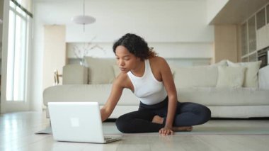 Yoga farkındalığı meditasyonu çevrimiçi. Afrikalı kadın evdeki bilgisayarında online derslerle yoga yapıyor. Lotus 'ta oturan kadın meditasyon yapıyor. Nefes egzersizi yapan bir kız. Evde yoga.