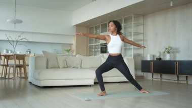 Yoga fitness antrenmanı. Sağlıklı Afrikalı kız evde yoga yapıyor. Pilates antrenmanı yapan bir kadın, yoga minderiyle spor yapıyor. Kız kilo vermek için antrenman yapıyor. Spor uygunluğu
