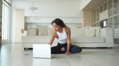 Yoga fitness antrenmanı online. Afrikalı kadın evdeki bilgisayarında online derslerle yoga yapıyor. Yoga minderinde spor yapan bir kız. Kadın kilo vermek için egzersiz yapıyor. Spor uygunluğu