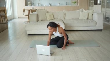 Yoga fitness antrenmanı online. Afrikalı kadın evdeki bilgisayarında online derslerle yoga yapıyor. Yoga minderinde spor yapan bir kız. Kadın kilo vermek için egzersiz yapıyor. Spor uygunluğu