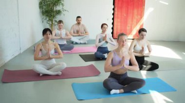 Yoga farkındalığı meditasyonu. Yoga sağlık farkındalığı meditasyonu için stüdyoda egzersiz yapan bir grup sporcu. Nilüfer çiçeğinde oturup yoga yapan erkek kadınlar meditasyon yapıyor.