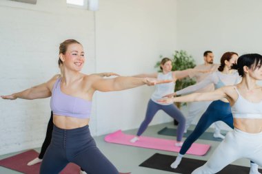 Yoga sınıfı pilates egzersizi. Bir grup sporcu, yoga sağIık meditasyonu için stüdyo sınıfında egzersiz yapıyor. Spor salonunda yoga yapan erkek antrenörler. Spor salonunda esneme hareketleri yapan kadınlar.