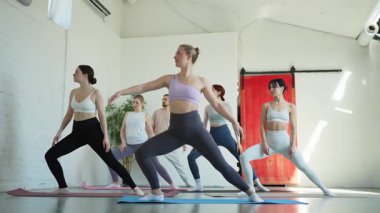 Yoga sınıfı pilates egzersizi. Bir grup sporcu, yoga sağIık meditasyonu için stüdyo sınıfında egzersiz yapıyor. Spor salonunda yoga yapan erkek antrenörler. Spor salonunda esneme hareketleri yapan kadınlar.