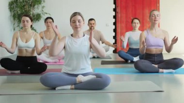 Yoga farkındalığı meditasyonu. Yoga sağlık farkındalığı meditasyonu için stüdyoda egzersiz yapan bir grup sporcu. Nilüfer çiçeğinde oturup yoga yapan erkek kadınlar meditasyon yapıyor.