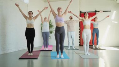 Yoga sınıfı pilates egzersizi. Bir grup sporcu, yoga sağIık meditasyonu için stüdyo sınıfında egzersiz yapıyor. Spor salonunda yoga yapan erkek antrenörler. Spor salonunda esneme hareketleri yapan kadınlar.