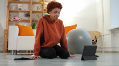 Yoga mindfulness meditation. Young healthy african girl practicing yoga at home. Woman sitting in lotus pose on yoga mat meditating smiling relaxing indoor. Girl doing breathing practice. Yoga at home