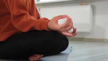 Yoga farkındalığı meditasyonu. Çene mudra hareketi yapan kadın elleri. Afrikalı kız evde yoga yapıyor. Lotus 'ta oturan kadın yoga minderinde poz veriyor içeride meditasyon yapıyor. Nefes egzersizi yapan kız.