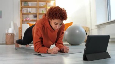 Fitness Workout training. Young healthy fit african girl doing plank exercise on yoga mat on floor at home. Athletic woman in sportswear training pilates. Sport and fitness