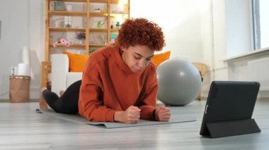 Fitness Workout training. Young healthy fit african girl doing plank exercise on yoga mat on floor at home. Athletic woman in sportswear training pilates. Sport and fitness