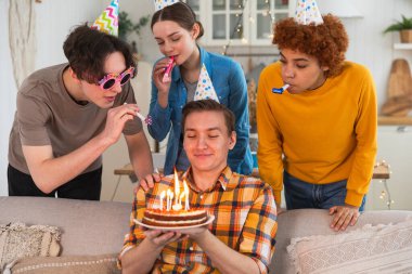 Bir dilek tut. Parti şapkası takmış bir adam doğum günü pastasında yanan mumları üflüyor. Doğum günün kutlu olsun. Arkadaş grubu adama mutlu yıllar diliyor. İnsanlar doğum gününü evde partiyle kutluyor.
