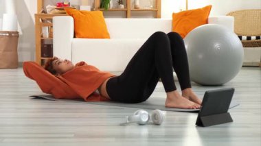 Fitness Workout training. Young healthy fit african girl doing bicycle crunch abs exercise on yoga mat on floor at home. Athletic woman in sportswear is pumping abdominals. Sport and fitness