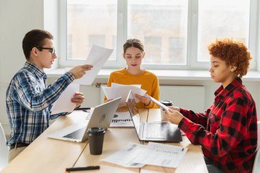 Takım çalışması beyin fırtınası. Çeşitli meslektaşlar birlikte çalışarak mali istatistikleri tartışırlar. Bir grup mutlu modern insan yaratıcı ofiste oturmuş iş tartışıyorlar. Genç profesyonel takım