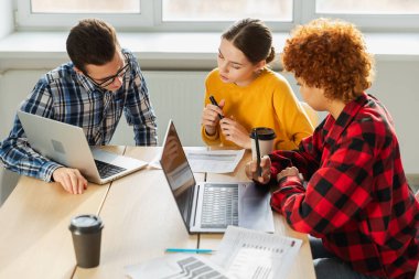 Takım çalışması beyin fırtınası. Çeşitli meslektaşlar birlikte çalışarak mali istatistikleri tartışırlar. Bir grup mutlu modern insan yaratıcı ofiste oturmuş iş tartışıyorlar. Genç profesyonel takım