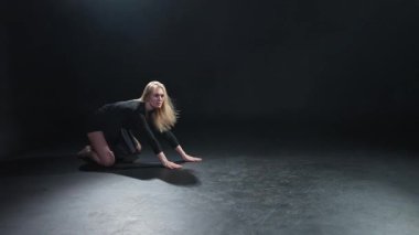 Siyah arka planda dumanla poz veren çağdaş kadın dansçı. Yetişkin kadın sanatçı ifade ile dans ediyor. Modern balerin karanlıkta dans ediyor. Tutku karanlıkta dans eder. Esneklik dengesi