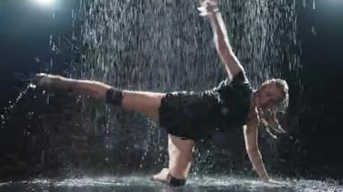 Siyah arka planda yağmur suyunda poz veren çağdaş kadın dansçı. Dişi sanatçı ifade ile dans ediyor. Modern balerin karanlıkta dans ediyor. Tutku karanlıkta dans eder. Esneklik dengesi