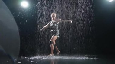 Siyah arka planda yağmur suyunda poz veren çağdaş kadın dansçı. Dişi sanatçı ifade ile dans ediyor. Modern balerin karanlıkta dans ediyor. Tutku karanlıkta dans eder. Esneklik dengesi
