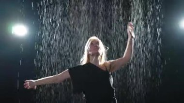 Siyah arka planda yağmur suyunda poz veren çağdaş kadın dansçı. Dişi sanatçı ifade ile dans ediyor. Modern balerin karanlıkta dans ediyor. Tutku karanlıkta dans eder. Esneklik dengesi