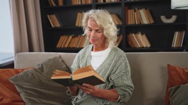 Huzur, evde kitap okuyan yaşlı ve yaşlı bir kadın. Olgun bir kadın dinleniyor. Evde tek başına sakin bir gün geçiriyor. Yetişkin kadın boş zamanlarını kitap okuyarak geçiriyor. Emeklilik konsepti