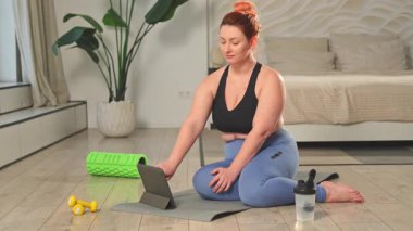 Yoga fitness antrenmanı online. Evde internet uygulaması dersleriyle esneme alıştırması yapan bir kadın. Artı ev içinde yoga minderiyle spor egzersizi yapan beden bir kadın. Kız kilo vermek için antrenman yapıyor.