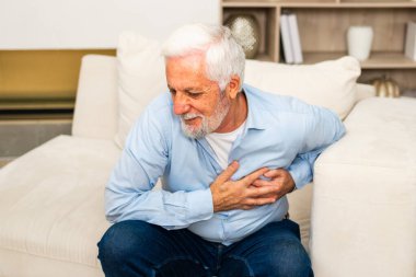 Kalp krizi, kalp krizi. Memnuniyetsiz orta yaşlı adam göğüs ağrısı çekiyor kalp krizi geçiriyor evde sağlık sorunları var. Yaşlı büyükbaba göğsüne dokunuyor ve damar tıkanıklığı yaşıyor.