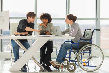 Takım çalışması beyin fırtınası. Çeşitli çok ırklı iş arkadaşları olan kadın engelliler için birlikte çalışıyor. Yaratıcı ofiste oturup iş konuşan bir grup insan. Genç profesyonel takım