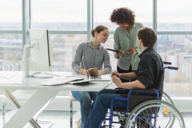 Takım çalışması beyin fırtınası. Çeşitli çok ırklı meslektaşlar birlikte çalışan engelli insanlar için sandalyede oturuyor. Yaratıcı ofiste oturup iş konuşan bir grup insan. Genç profesyonel takım