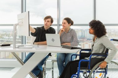 Takım çalışması beyin fırtınası. Çeşitli çok ırklı iş arkadaşları olan kadın engelliler için birlikte çalışıyor. Yaratıcı ofiste oturup iş konuşan bir grup insan. Genç profesyonel takım
