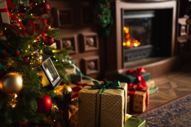 Klasik Noel süslemeli oturma odası kütüphanesinde şömineli bir sürü hediye kutusu var. Noel hediyesi köknar ağacının yanında. Modern klasik iç tasarım dairesi. Evde Noel arifesi