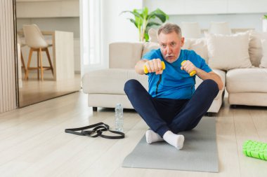 Fitness antrenmanı. Üst düzey boksör dambılları kaldırıyor. Yetişkin, sağlıklı bir adam evde spor yapıyor. Büyükbabanın rehabilitasyonu var. Sağlık hizmetleri sağlıklı yaşam tarzı