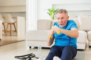 Fitness antrenmanı. Üst düzey boksör dambılları kaldırıyor. Yetişkin, sağlıklı bir adam evde spor yapıyor. Büyükbabanın rehabilitasyonu var. Sağlık hizmetleri sağlıklı yaşam tarzı