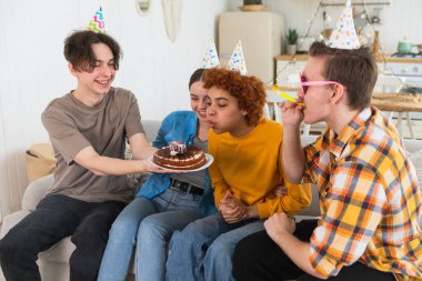 Bir dilek tut. Parti şapkası takan bir kadın doğum günü pastasında yanan mumları üflüyor. Doğum günün kutlu olsun. Bir grup arkadaş kızın doğum gününü kutluyor. İnsanlar doğum gününü evde partiyle kutluyor.