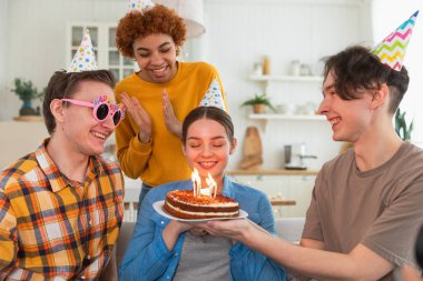 Bir dilek tut. Parti şapkası takan bir kadın doğum günü pastasında yanan mumları üflüyor. Doğum günün kutlu olsun. Bir grup arkadaş kızın doğum gününü kutluyor. İnsanlar doğum gününü evde partiyle kutluyor.