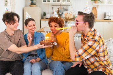 Bir dilek tut. Parti şapkası takan bir kadın doğum günü pastasında yanan mumları üflüyor. Doğum günün kutlu olsun. Bir grup arkadaş kızın doğum gününü kutluyor. İnsanlar doğum gününü evde partiyle kutluyor.