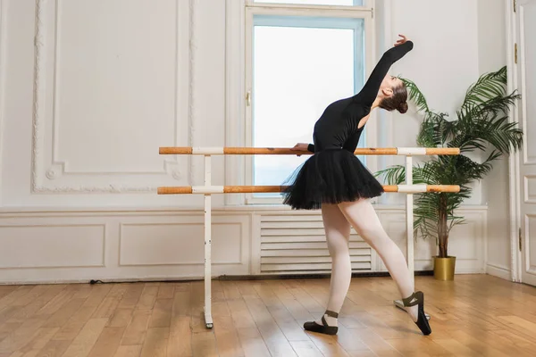 Tutu etekli genç balerin dans sınıfında bale pozisyonlarında dans ediyor. Dans stüdyosundaki genç klasik dansçı kadın. Bale sınıfı eğitim konsepti