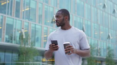 İyi sabahlar. Afrikalı bir adam şehirde akıllı telefon tutmak için kahve içiyor. Sosyal medya uygulamaları kullanarak internette cep telefonu sörfü yapan bir adam. İnternet haberleri cep telefonu bağımlılığı