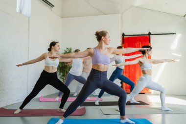Yoga sınıfı pilates egzersizi. Bir grup sporcu, yoga sağIık meditasyonu için stüdyo sınıfında egzersiz yapıyor. Spor salonunda yoga yapan erkek antrenörler. Spor salonunda esneme hareketleri yapan kadınlar.